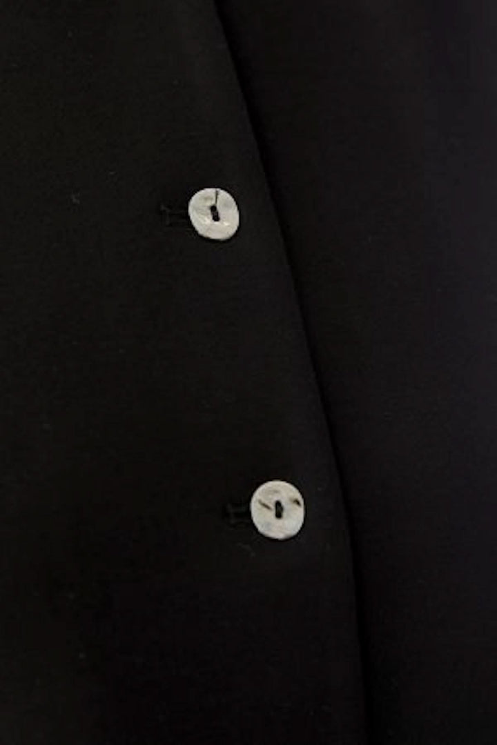Détail bouton du haut sans manches boutonné, design sobre et élégant en noir, parfait pour une tenue moderne et minimaliste.