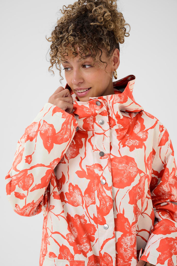 Femme portant l'Imperméable Olif avec motif floral expressif et coupe droite, parfait pour un style moderne et fonctionnel par temps pluvieux.