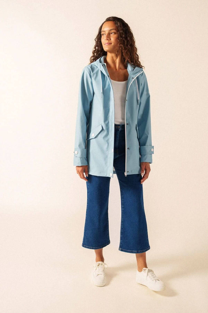 Femme portant l'Imperméable STE GAIA bleu clair, idéal pour la ville et la mer, confectionné en polyuréthane waterproof avec doublure en mesh.