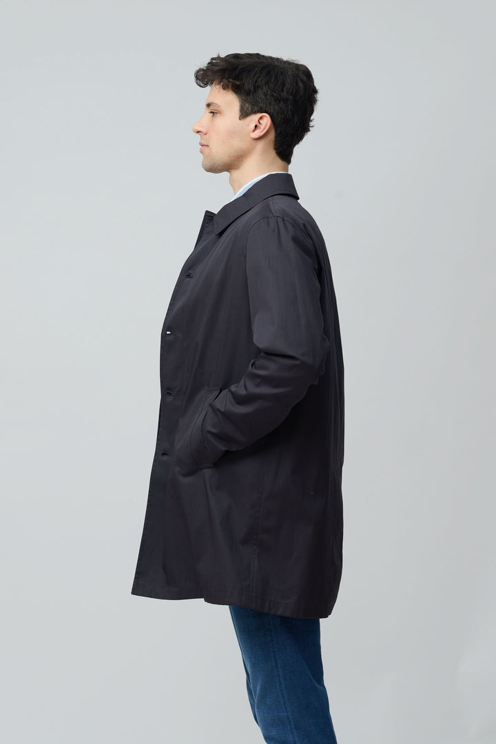 Homme portant un imperméable en gabardine de coton avec coupe droite et col chemise, idéal pour un usage urbain élégant et fonctionnel.