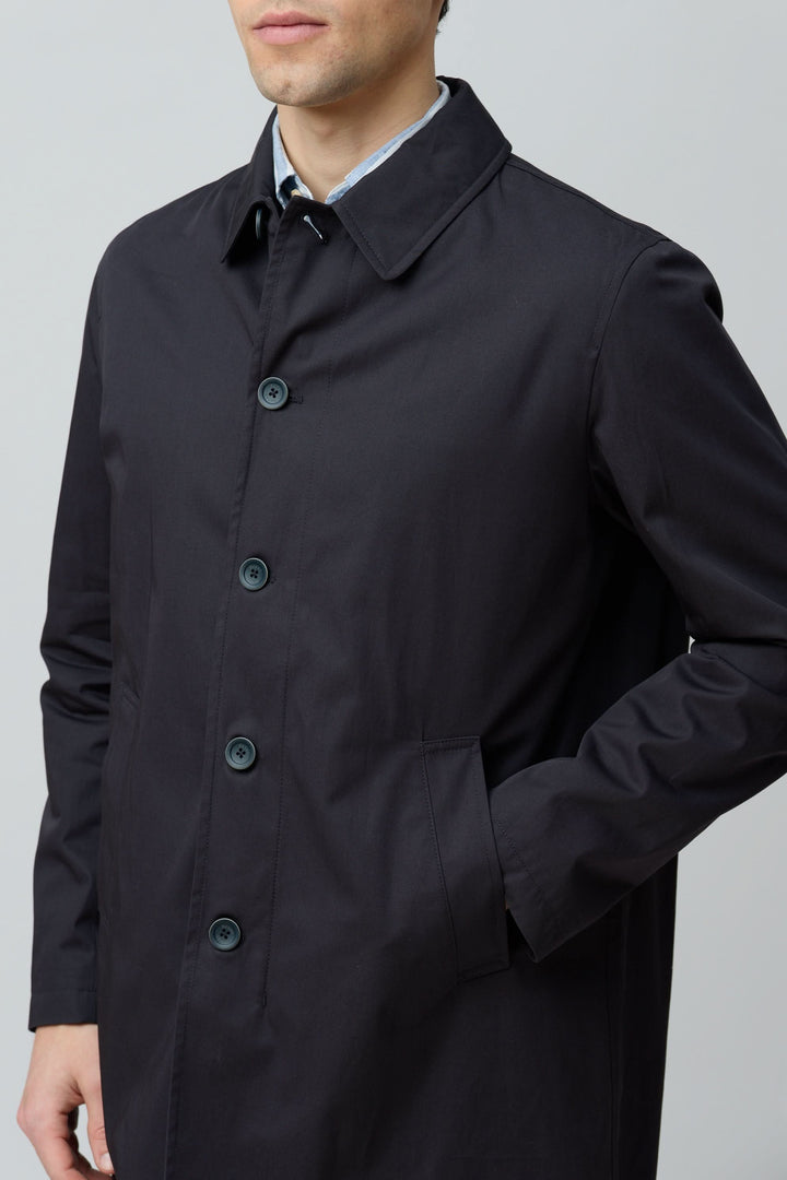 Homme portant un impermeable en gabardine de coton noir avec coupe droite et col chemise élégant.