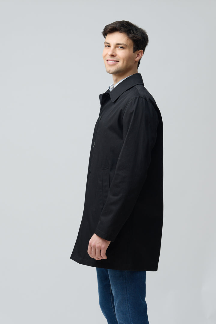 Homme portant un impermeable en gabardine de coton noir avec col chemise, allure intemporelle et élégance urbaine.