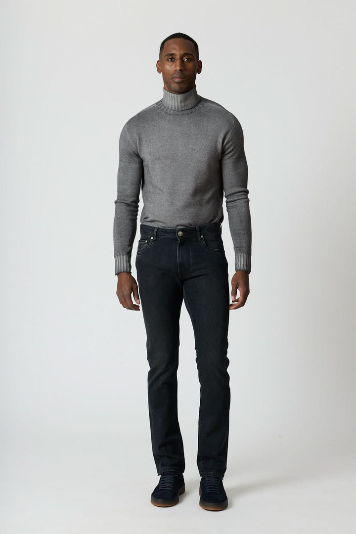 Homme portant un Jean 5 poches en denim stretch gris foncé avec col roulé gris et sneakers noires, style moderne et ajusté.