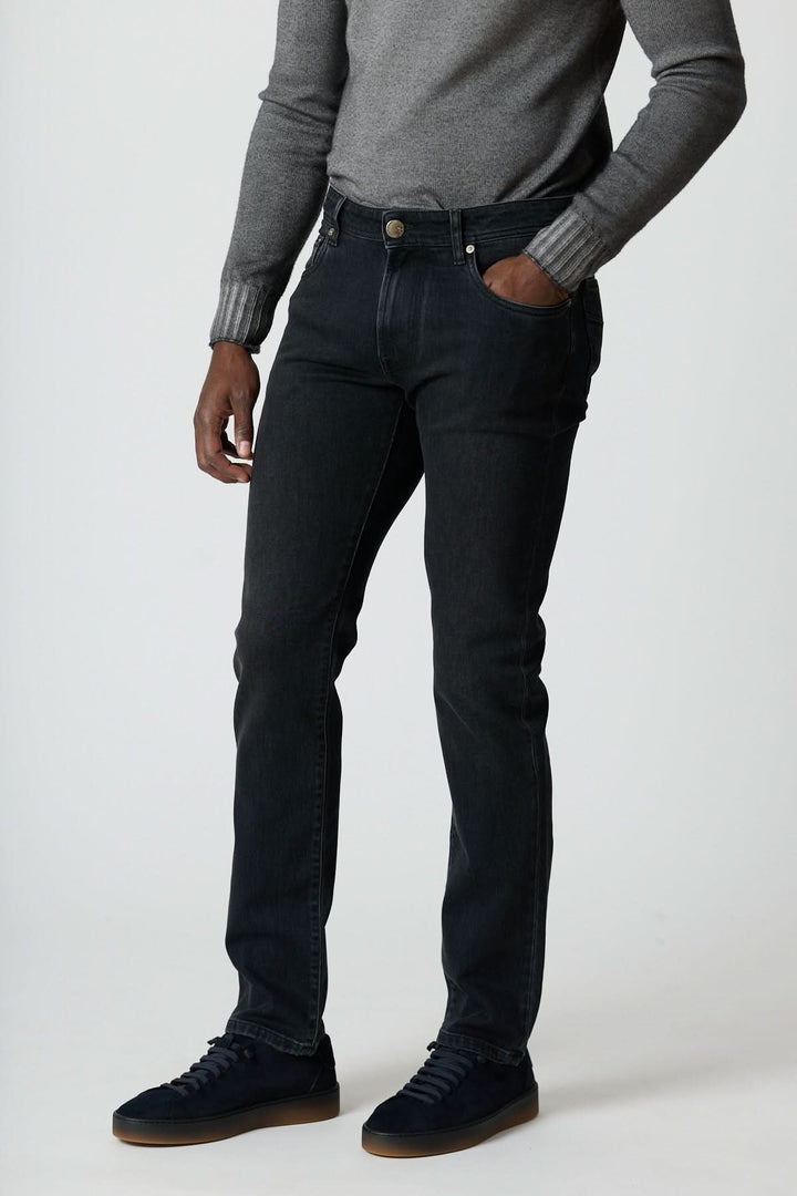 Jean 5 poches en denim stretch gris foncé, coupe ajustée, tenue impeccable, porté avec pull gris et sneakers propre.