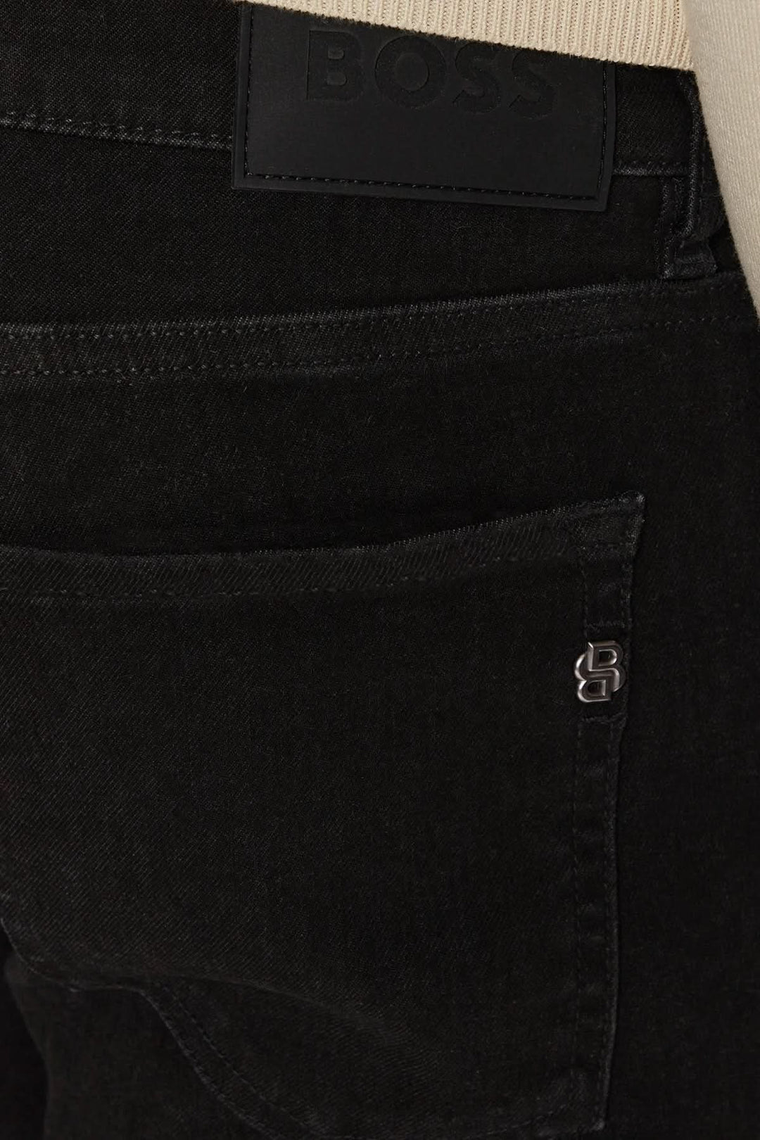 Détail des jeans noirs BOSS avec logo, présentation de la coupe slim fit et du tissu denim extensible.