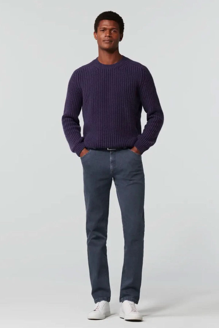 Homme portant un pull en maille violet et un jean slim en denim, avec des baskets blanches. Look décontracté et élégant.