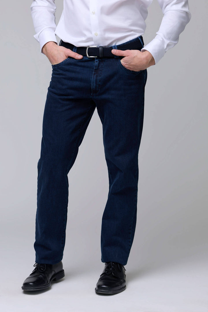 Jean coupe droite en denim extensible, homme en chemise blanche, sur fond gris, idéal pour un style moderne et quotidien.