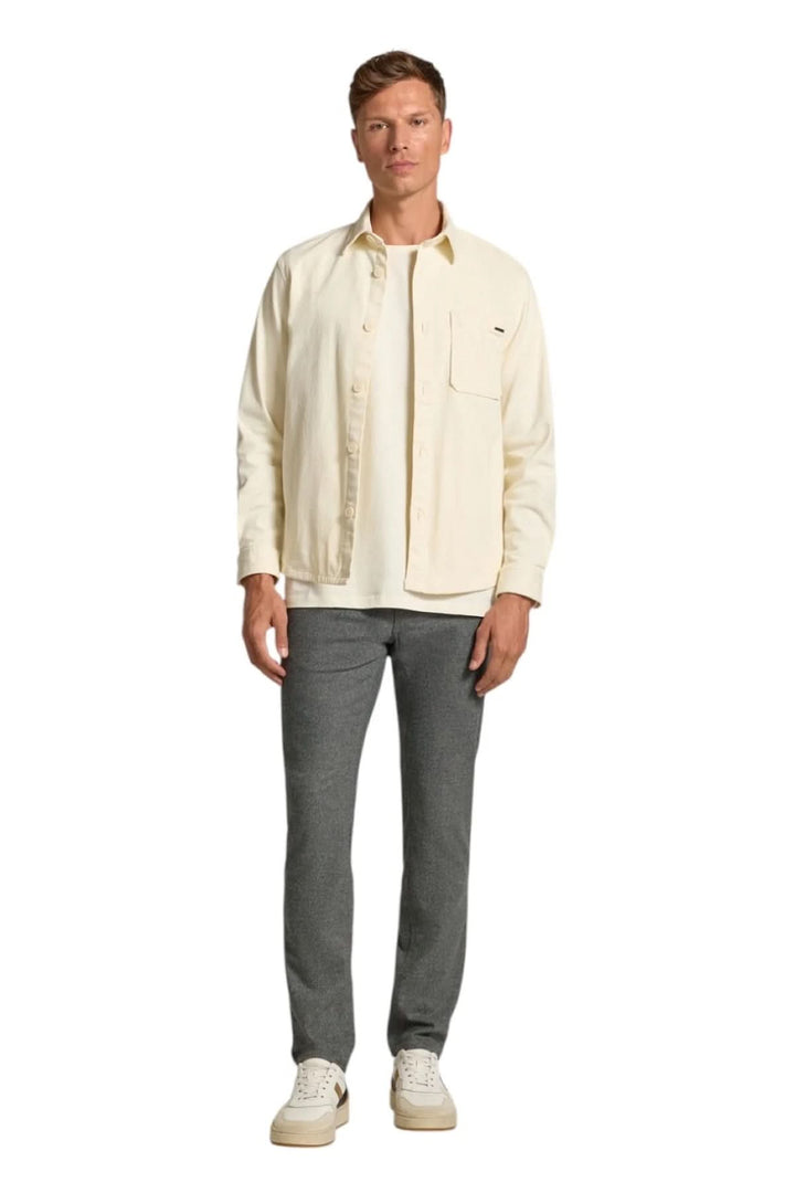 Homme portant un jean en flanelle à coupe ajustée et une veste crème, mode chic et décontractée.
