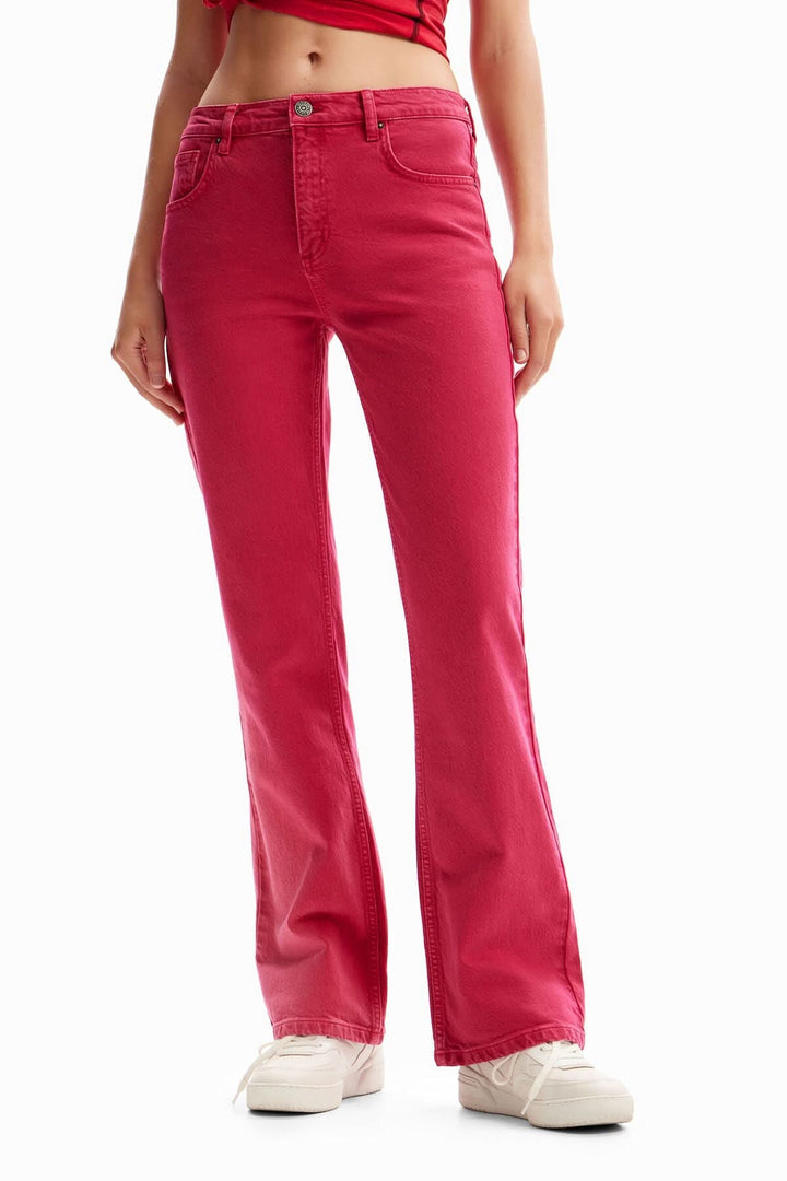 Jean flare uni rose, taille mi-haute, évasé à partir du genou, portée avec un haut rouge.