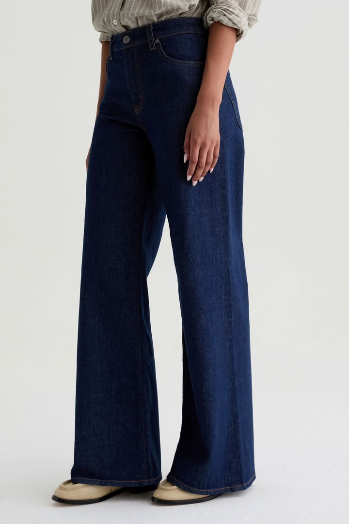 Jean à jambe large en denim avec coupe taille haute et finition élégante sur mannequin, style moderne et raffiné.