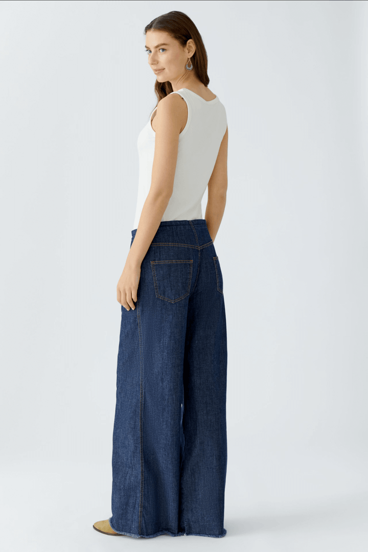 Femme portant un jean ultra léger à taille mi-haute avec coupe ample et ceinture à cordon devant fond blanc.