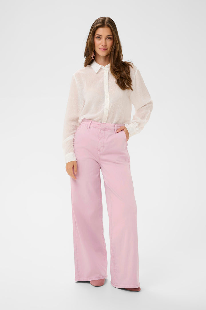 Modèle portant le Jeans Visti rose à jambe large avec une blouse blanche, coupe ample pour un style décontracté et élégant.