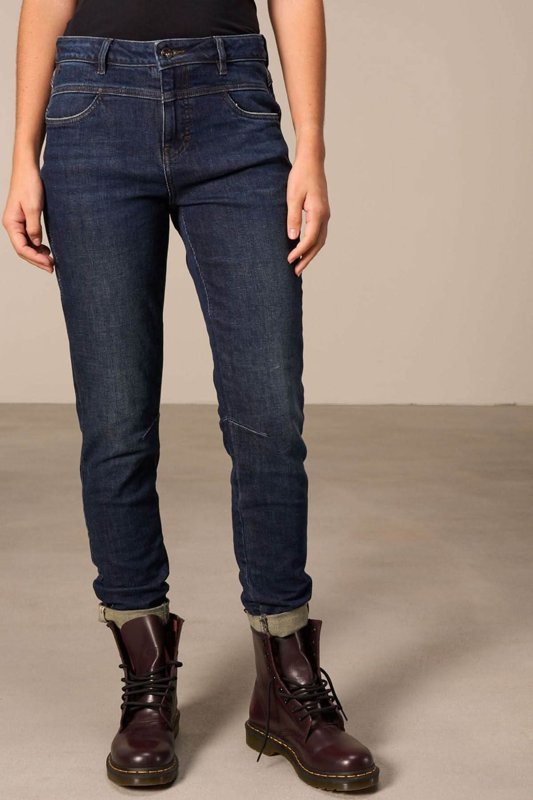 Jeans cheville effilée avec un look moderne, retroussés et décolorés, associés à des bottes noires.