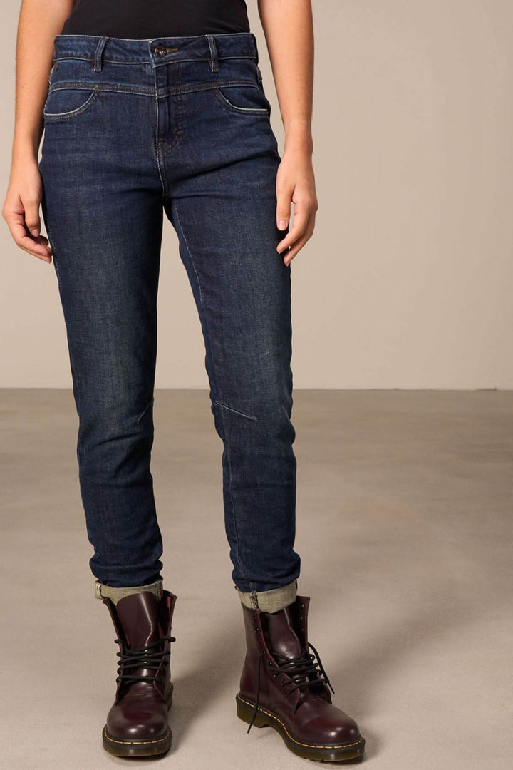 Jeans cheville effilée avec un look moderne, retroussés et décolorés, associés à des bottes noires.