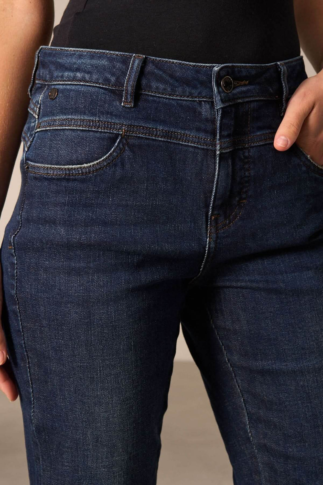 Jeans cheville effilée en denim foncé, offrant une coupe moderne et décontractée avec poches avant.