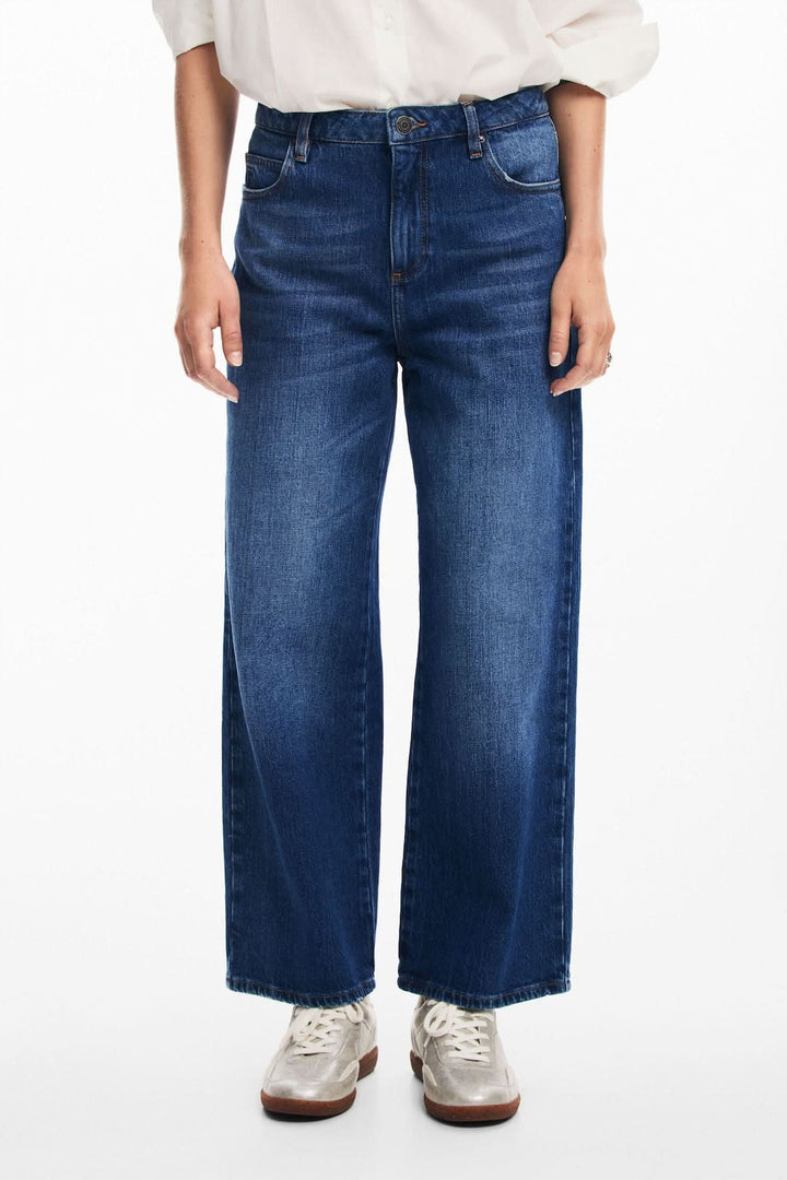 Jean ample à taille régulière, détails floraux, style décontracté, porté avec des baskets.