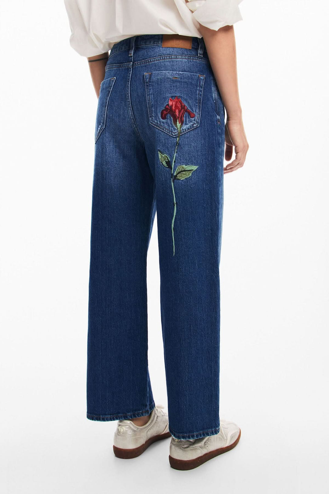 Jeans bleu ample avec broderie florale rouge à l'arrière, style décontracté et féminin.