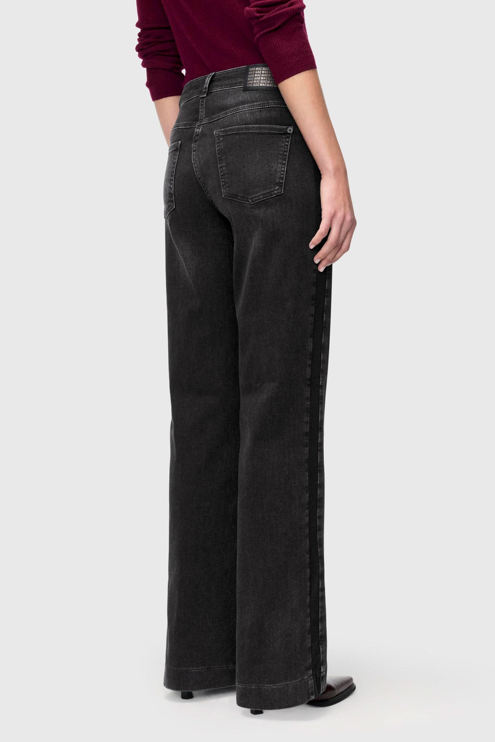 Jeans jambe large noir délavé avec coupe fluide et poches arrières, idéal pour un look rétro et tendance, porté avec un haut bordeaux.