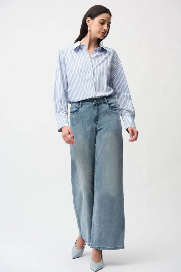 Femme portant un jeans à jambe large taille haute, moderne et fluide pour un style décontracté et soigné, avec une chemise rayée.