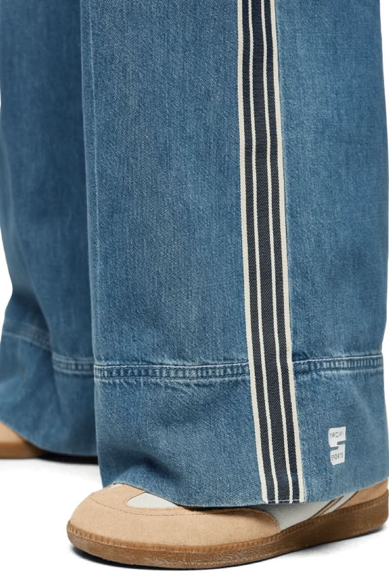 Jeans large à bandes contrastantes avec détails de bandes verticales sur les côtés, offrant une allure moderne et décontractée.