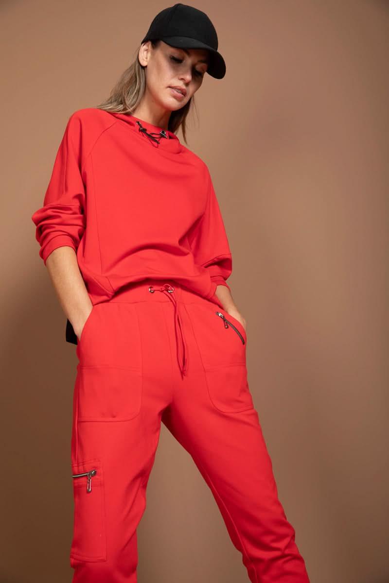Femme portant un jogging ajusté rouge avec poches latérales et taille élastique, affichant un look chic décontracté.