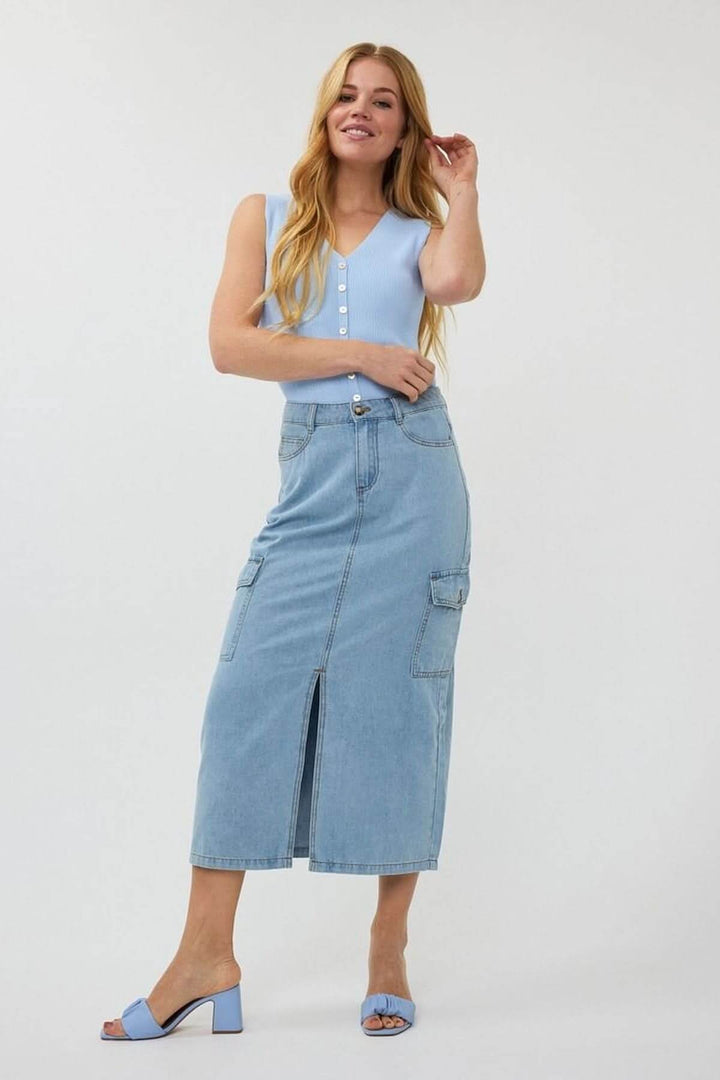 Jupe cargo en denim bleu avec poches, fente avant et coupe midi, portée avec un haut bleu et des sandales.