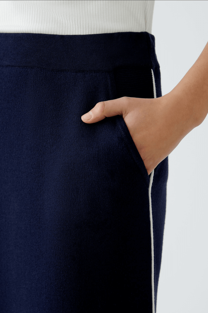Détail de la jupe droite en tricot avec poche et passepoil contrastant, offrant style et confort.
