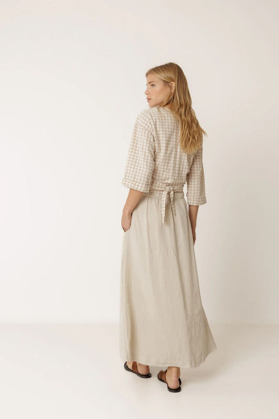 Femme portant une jupe midi fluide en lin, vue de dos, style élégant et naturel.