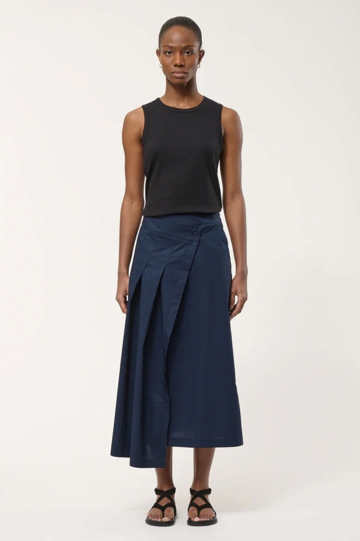 Femme portant une jupe midi portefeuille élégante avec un pli marqué, silhouette contemporaine, tombé net, parfait pour un style sophistiqué.