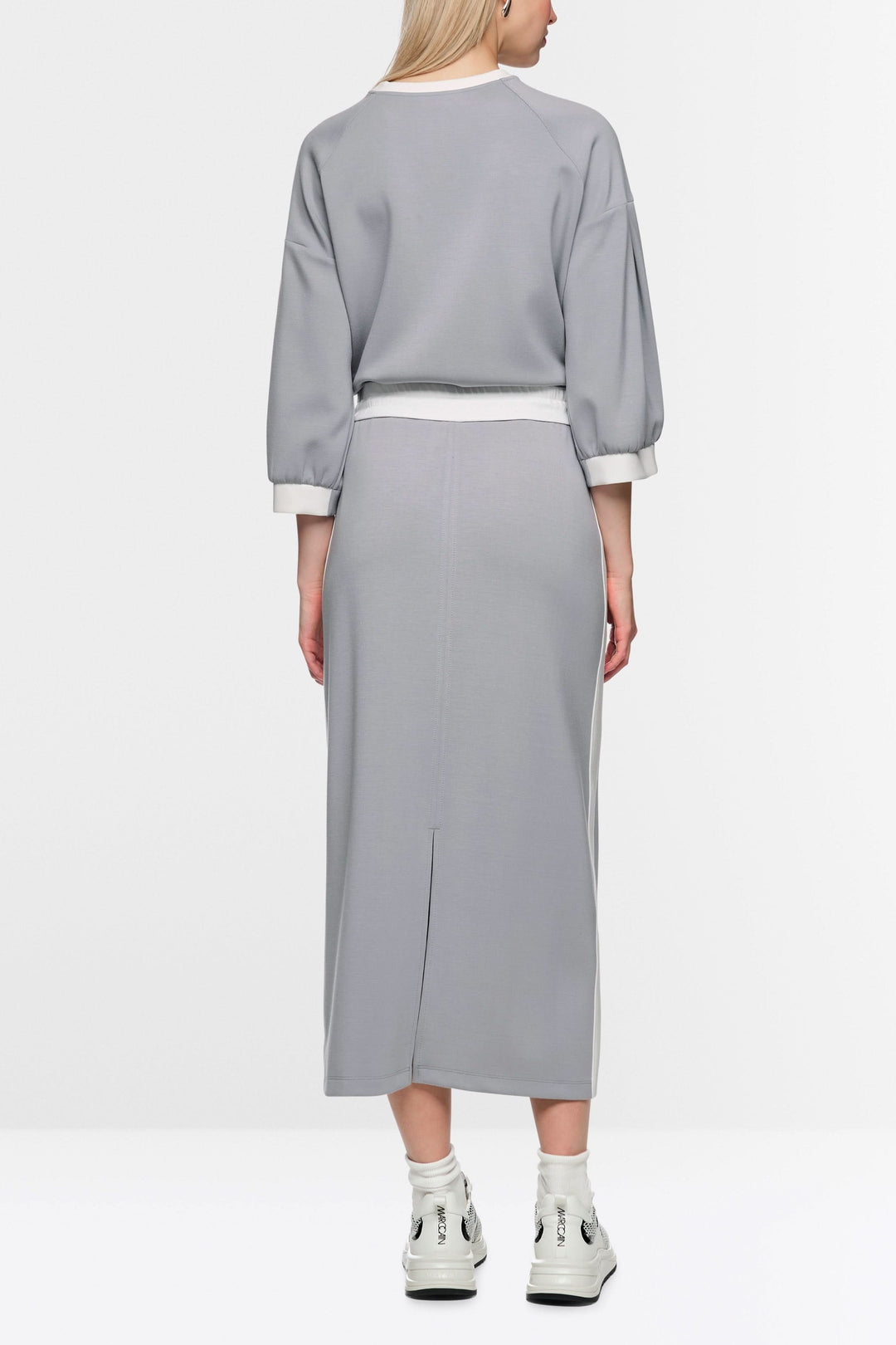 Femme portant une jupe midi sportive grise en tissu doux, avec bande contrastée, taille élastiquée et logo Marc Cain Sports.