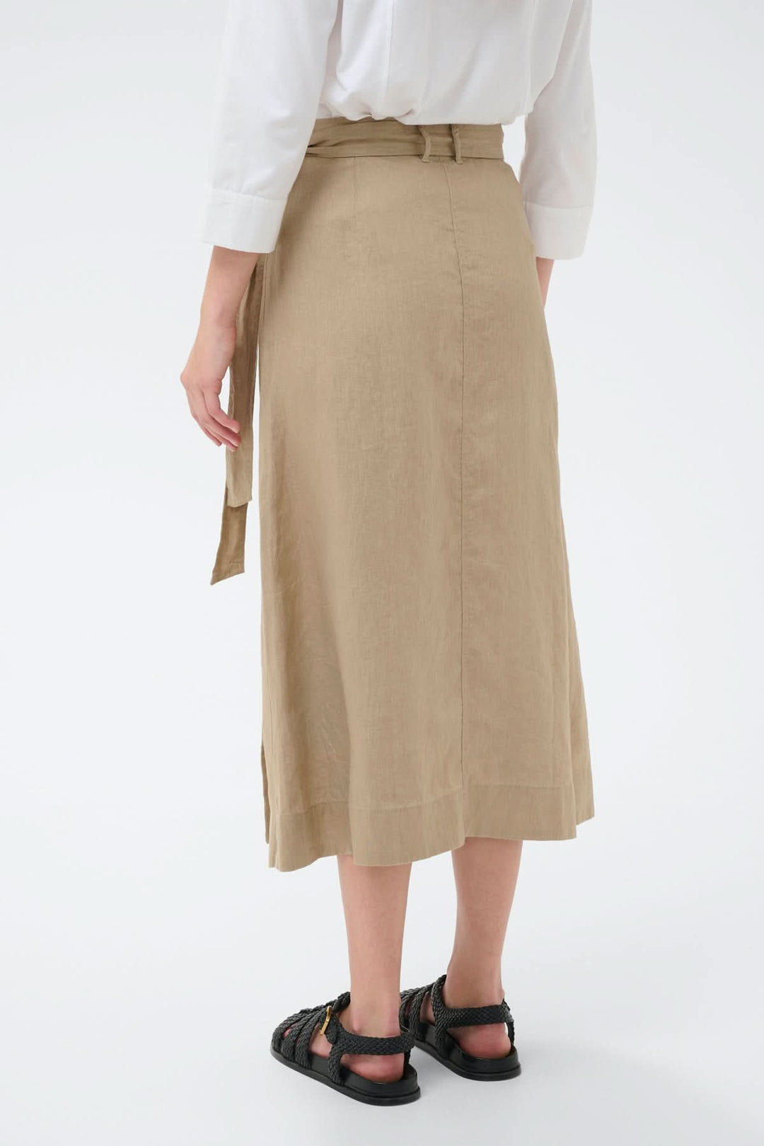 Femme portant une jupe porte-feuille Arbella beige vue de dos, coupe midi fluide.