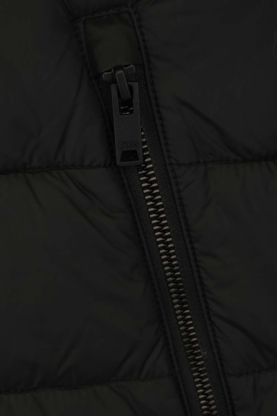 Zoom sur la fermeture éclair d'une veste matelassée BOSS, couleur noire, alliant confort et style.