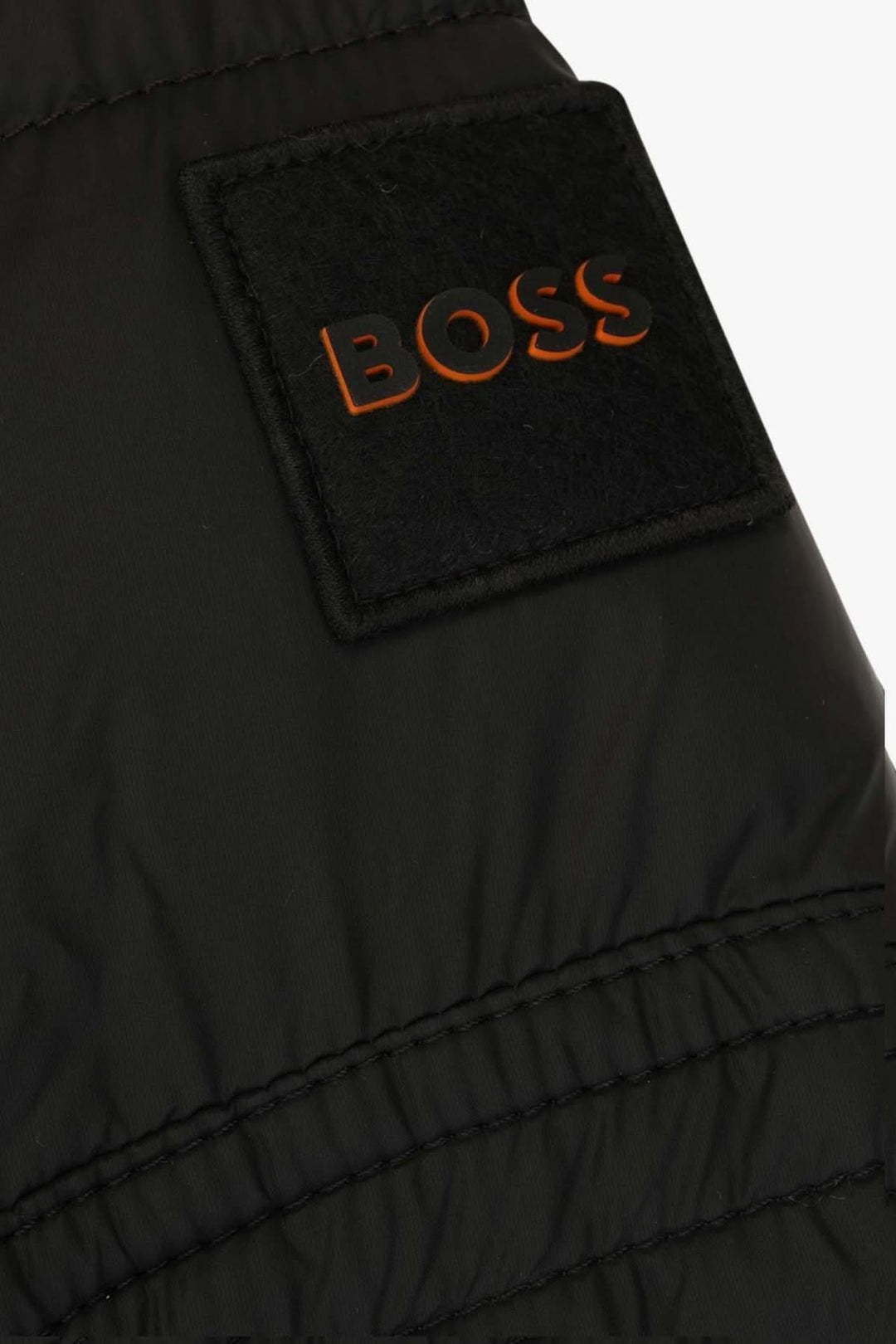 Détails du manteau Boss avec logo en relief sur l'empiècement matelassé.
