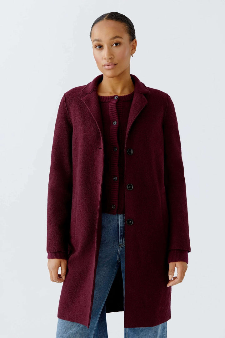Femme portant un Manteau Mayson bordeaux, coupe droite et longue, col tailleur classique, style chic décontracté avec jean.