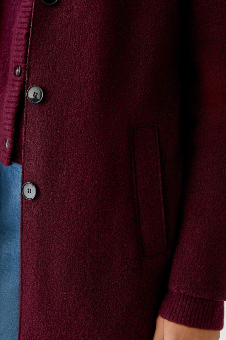 Détail du Manteau Mayson bordeaux avec coupe longue et boutons, parfait pour un look élégant et moderne en mi-saison.
