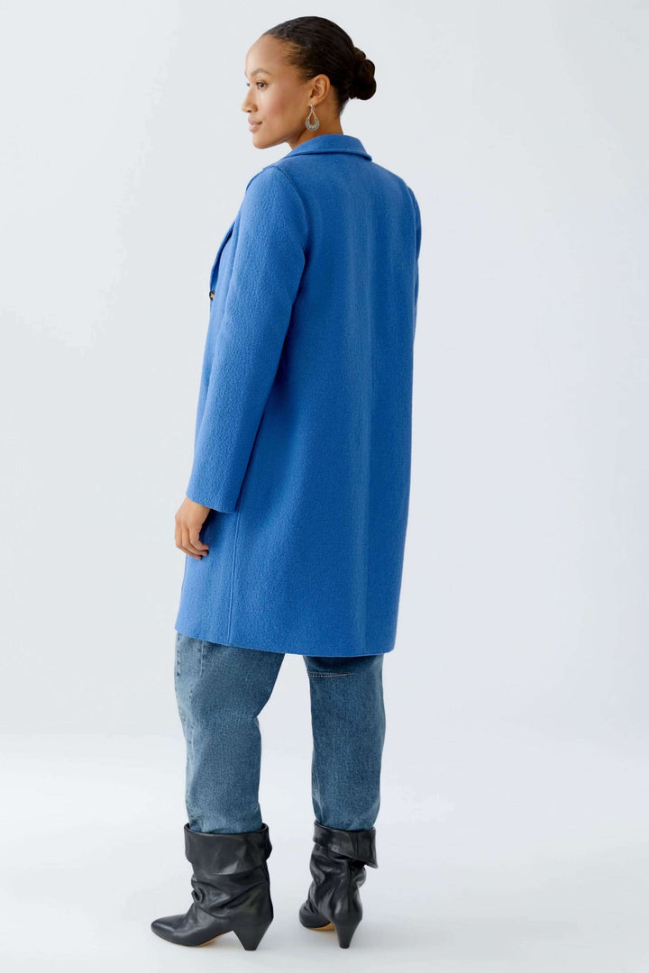 Femme portant un Manteau Mayson bleu, coupe longue, col tailleur classique, style élégant et moderne, tenue chic avec jean et bottes.