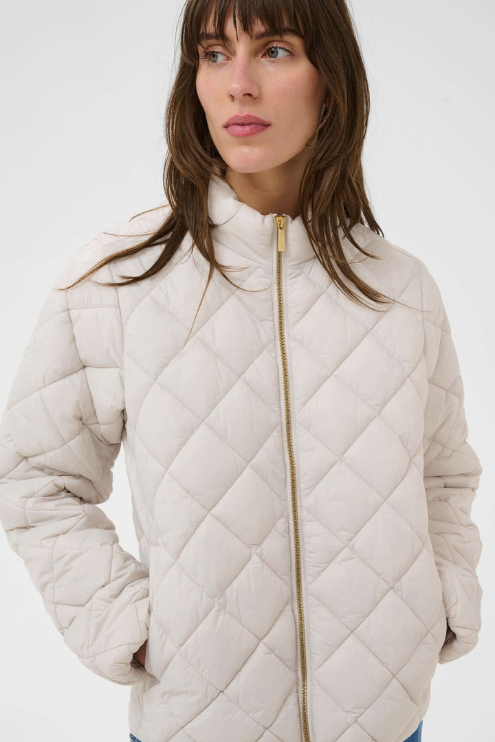 Femme portant un Manteau Olia matelassé avec col montant et fermeture éclair, idéal pour une allure moderne et pratique.