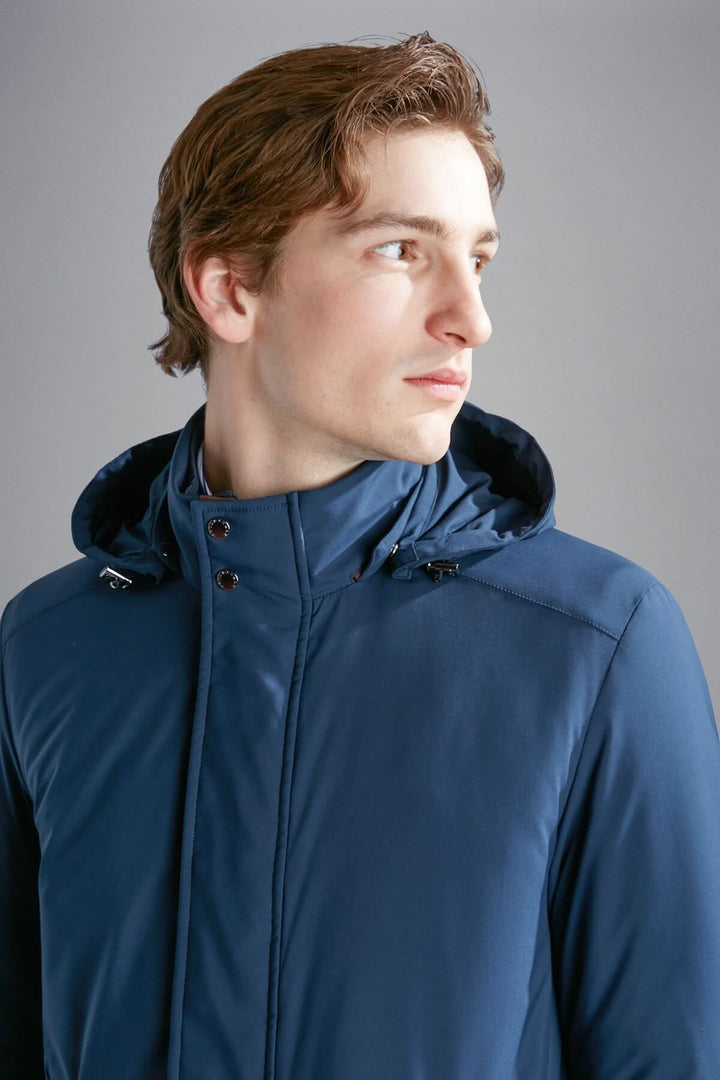 Homme portant un manteau d'hiver bleu marine avec capuche, parfait pour les journées froides.