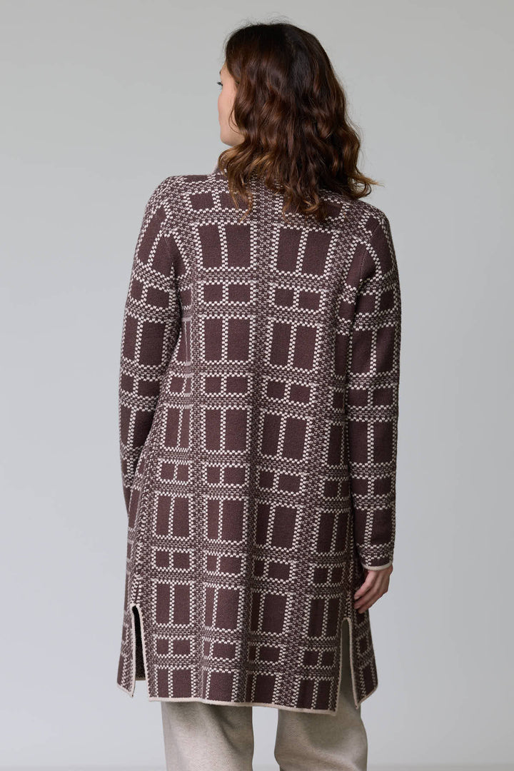 Femme portant un manteau en tricot à motif géométrique bicolore avec coupe droite et finitions contrastantes.