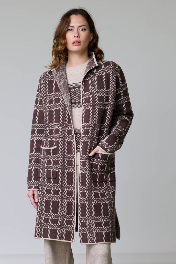 Femme portant un manteau en tricot à motif géométrique avec col à revers, poches plaquées, et finitions contrastantes, couleur bicolore.