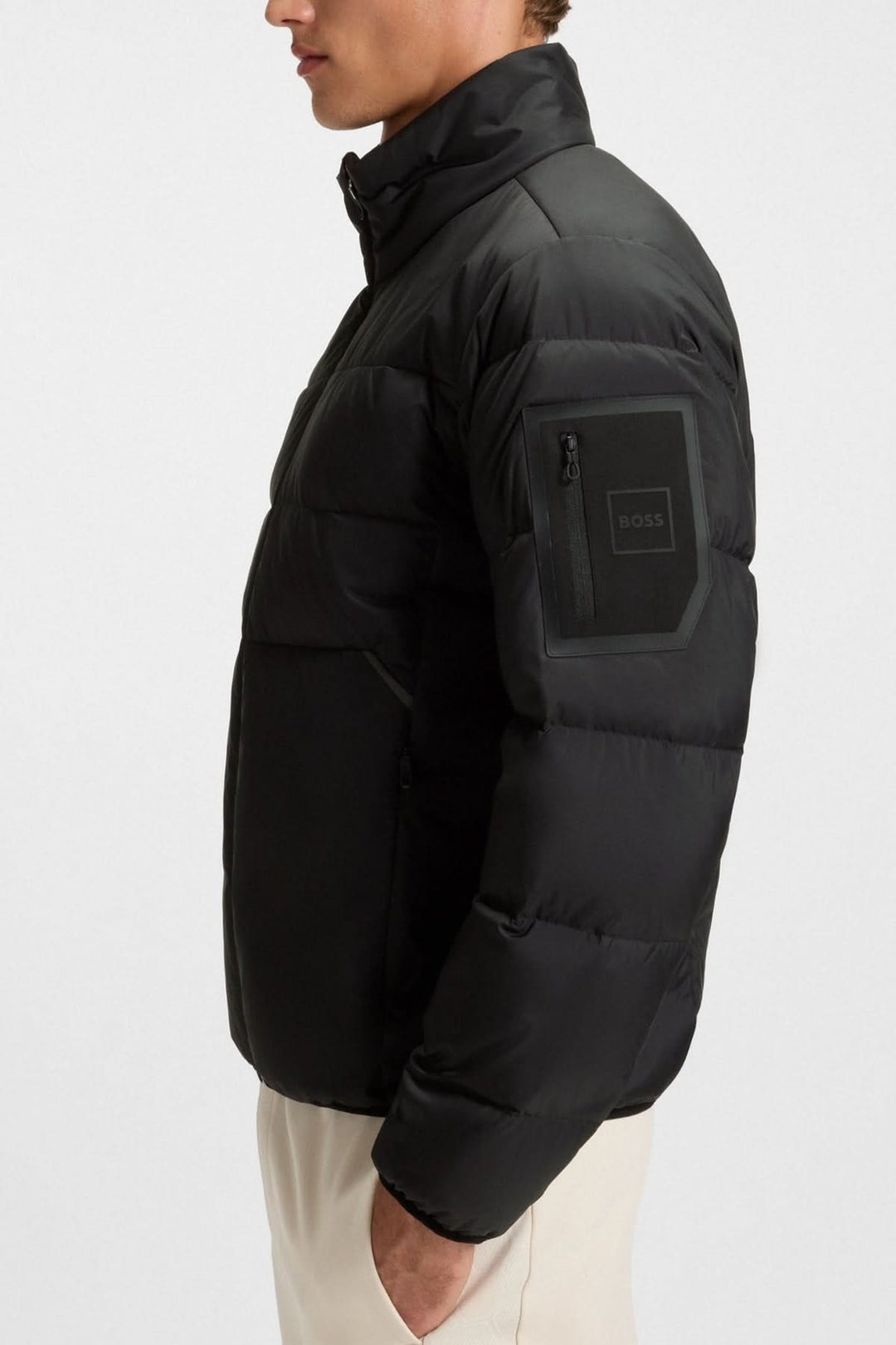 Homme portant un manteau matelassé déperlant en duvet avec poche sur la manche, BOSS, élégant et pratique pour la mi-saison.