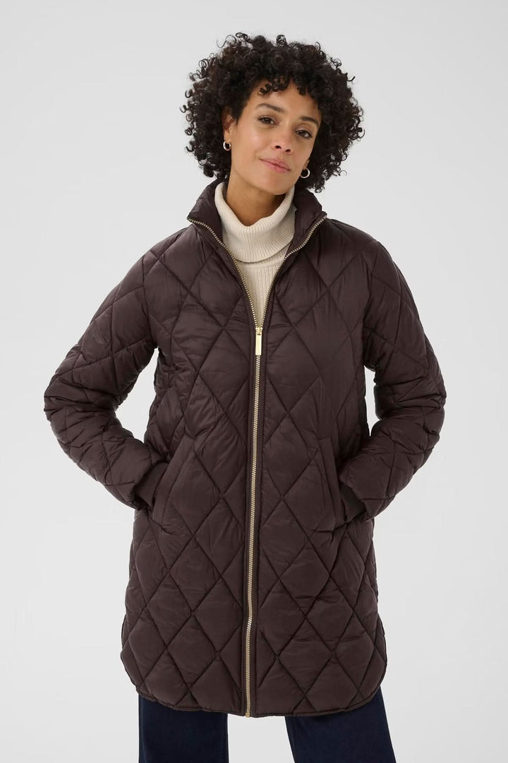 Manteau matelassé à losanges avec fermeture zippée dorée, porté par une femme au style chic et décontracté.