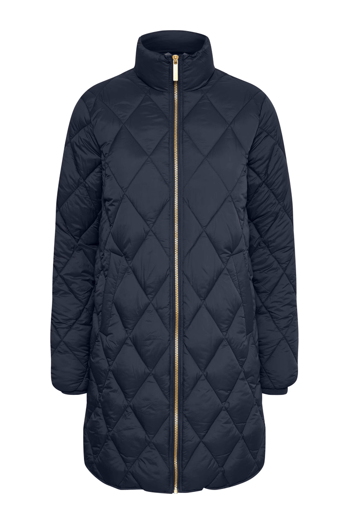 Manteau matelassé à losanges, long avec fermeture zippée dorée, idéal pour la mi-saison, porté avec jean évasé et col roulé.