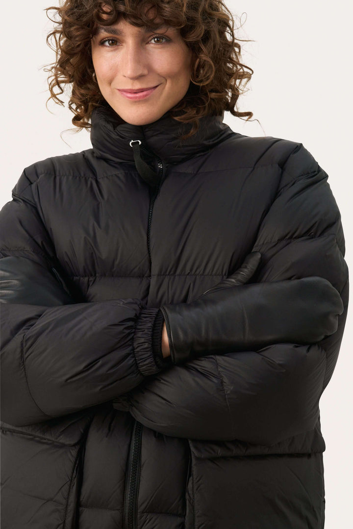 Femme portant Mitaines Fiori en cuir véritable avec un manteau noir, offrant élégance et chaleur pour l&