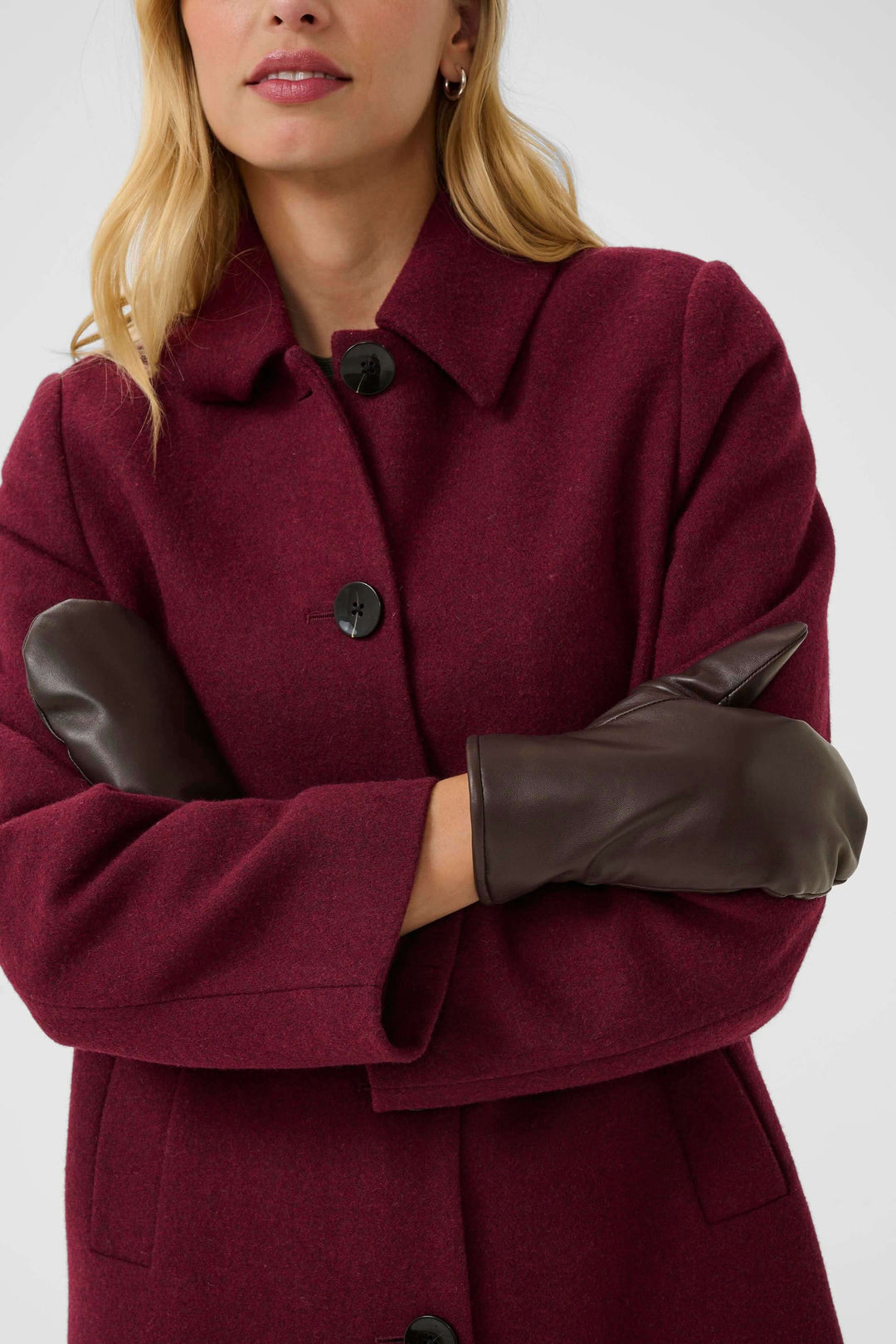 Femme portant des Mitaines Fiori en cuir véritable avec un manteau en laine bordeaux, style hivernal élégant et chaud.