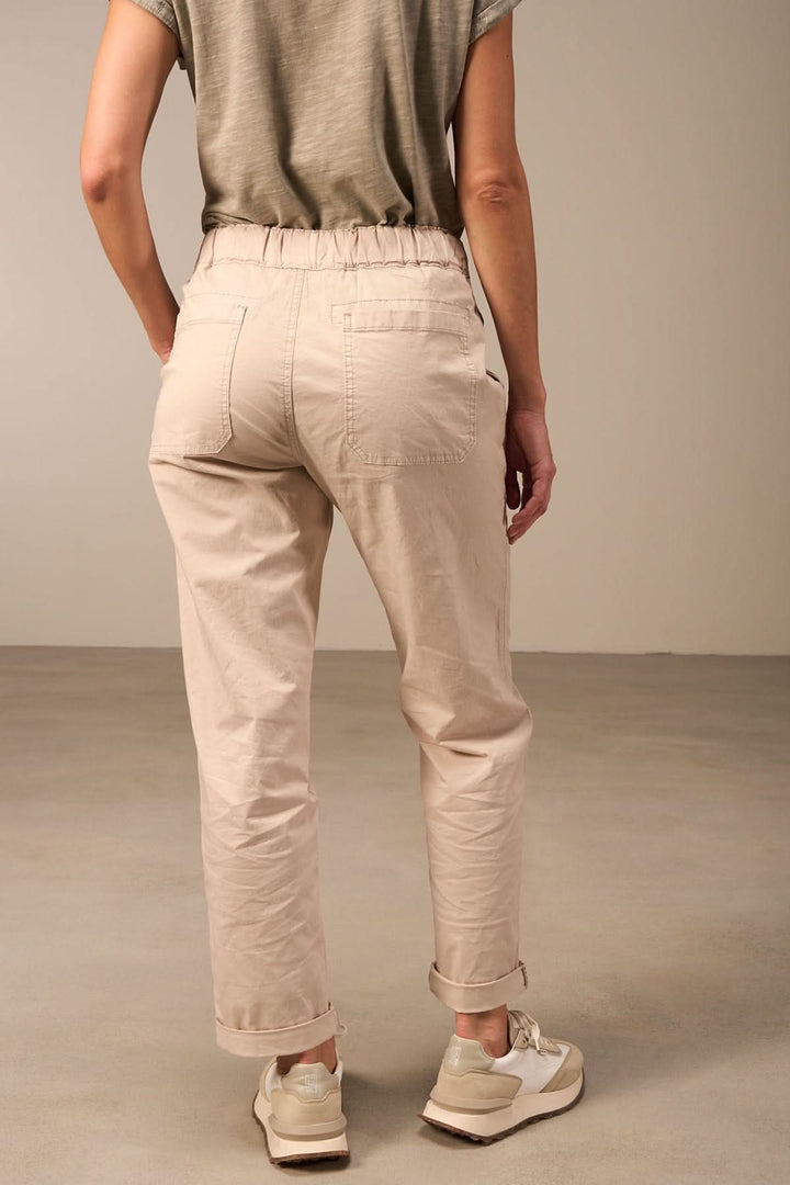 Femme portant un pantalon beige décontracté à taille élastique en vue arrière, style casual avec baskets.