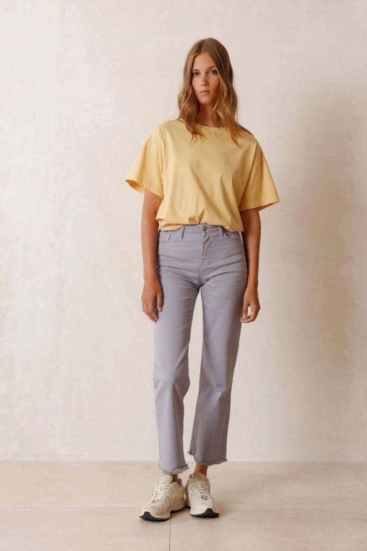 Modèle portant un t-shirt jaune avec un pantalon court gris et des baskets, sur fond neutre.