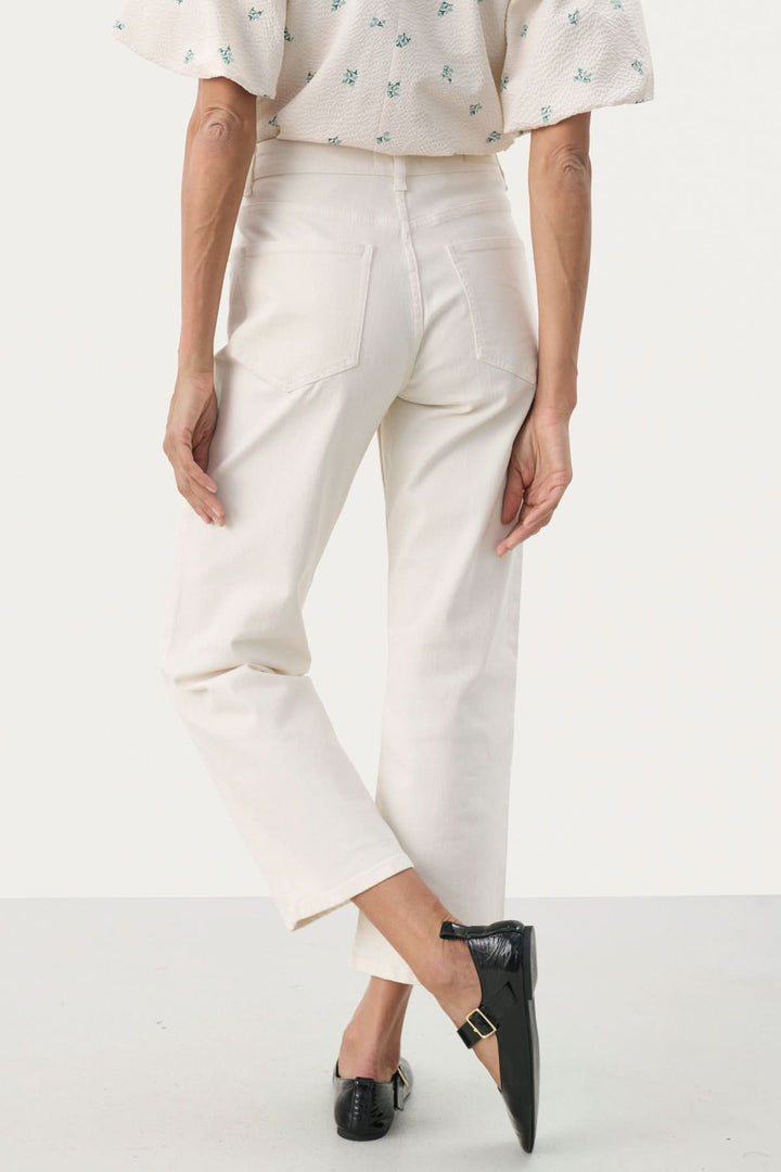 Pantalon Judya en denim blanc, coupe évasée et raccourcie, associé à un top à motifs pour un look décontracté chic.