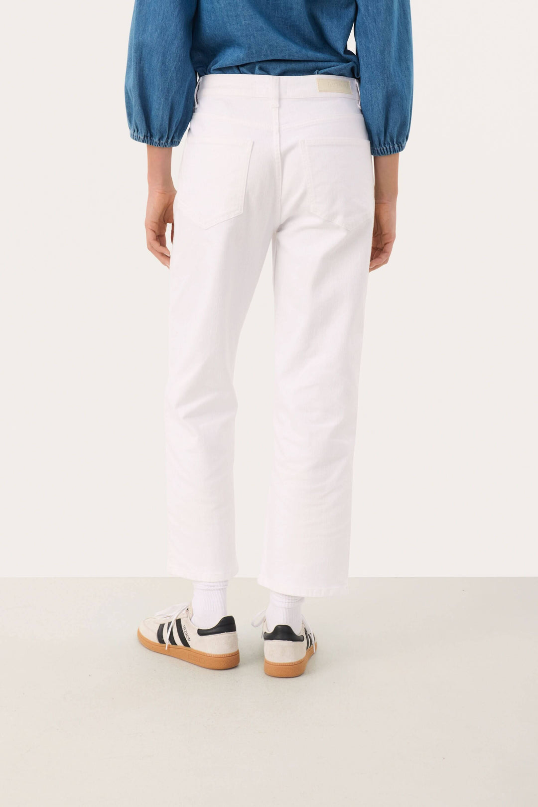 Pantalon Judya blanc, coupe évasée raccourcie, porté avec un haut en denim, style moderne et décontracté.