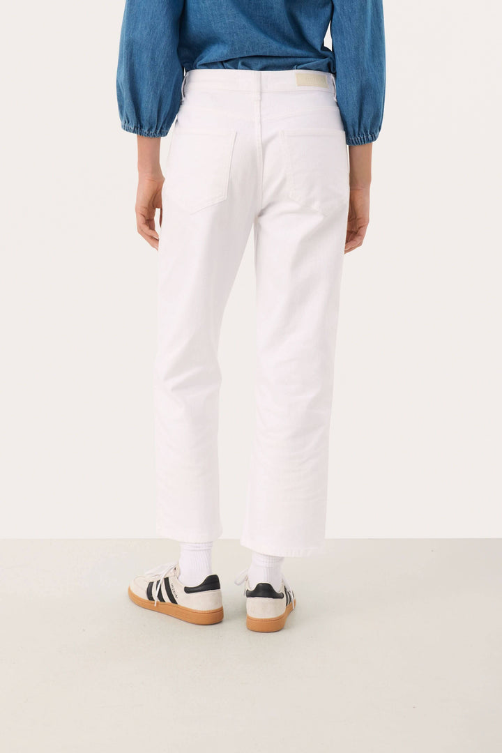 Pantalon Judya blanc, coupe évasée raccourcie, porté avec un haut en denim, style moderne et décontracté.